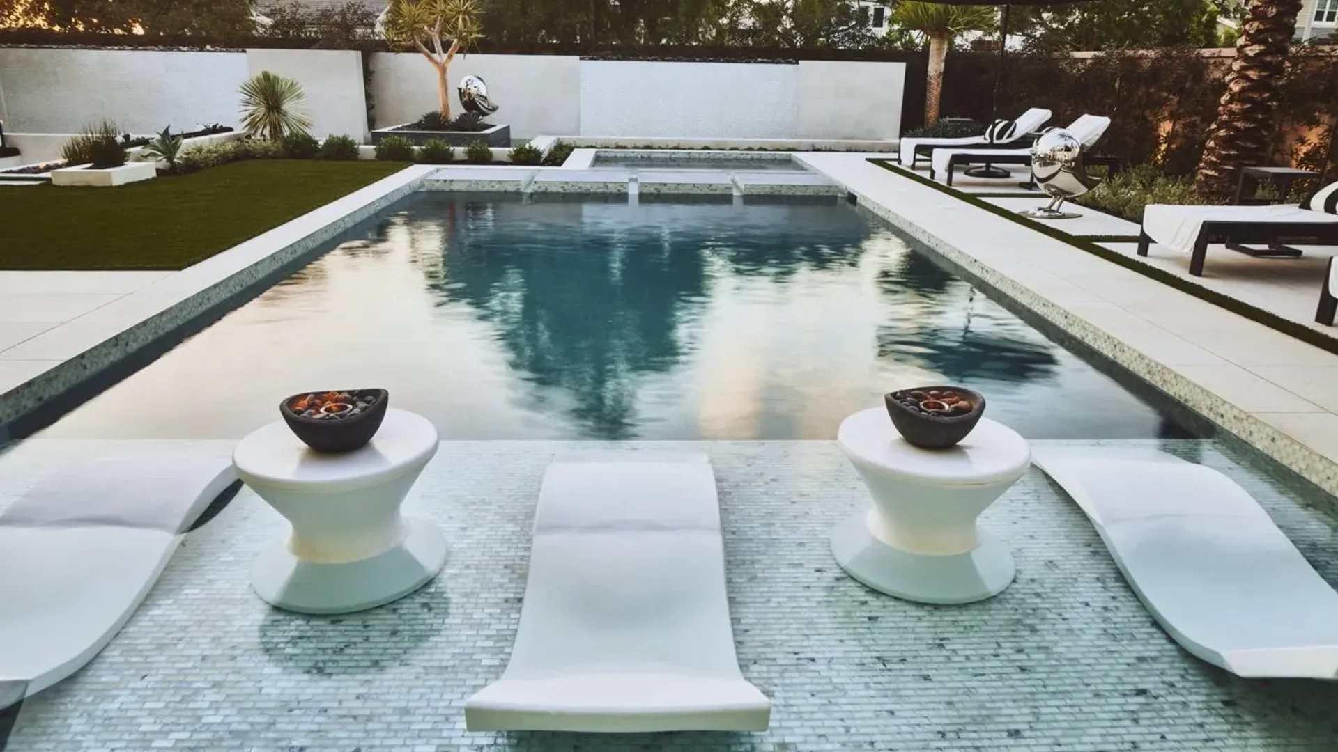 Custom luxury pool with modern lounge chairs, decorative bowls, and landscaped surroundings in Laguna Beach, emphasizing relaxation and outdoor living.