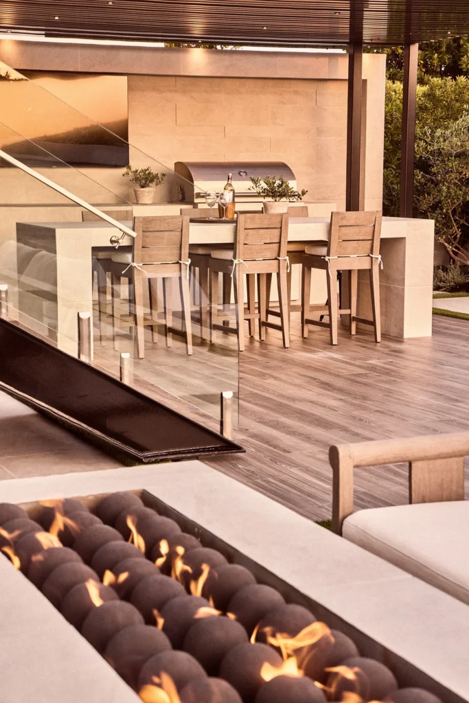 Mediterranean outdoor kitchen and patio design with fire feature and seating.